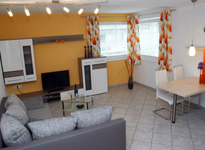 Innenperspektive des Wohnraumes mit Sofa, Essplatz und Küche